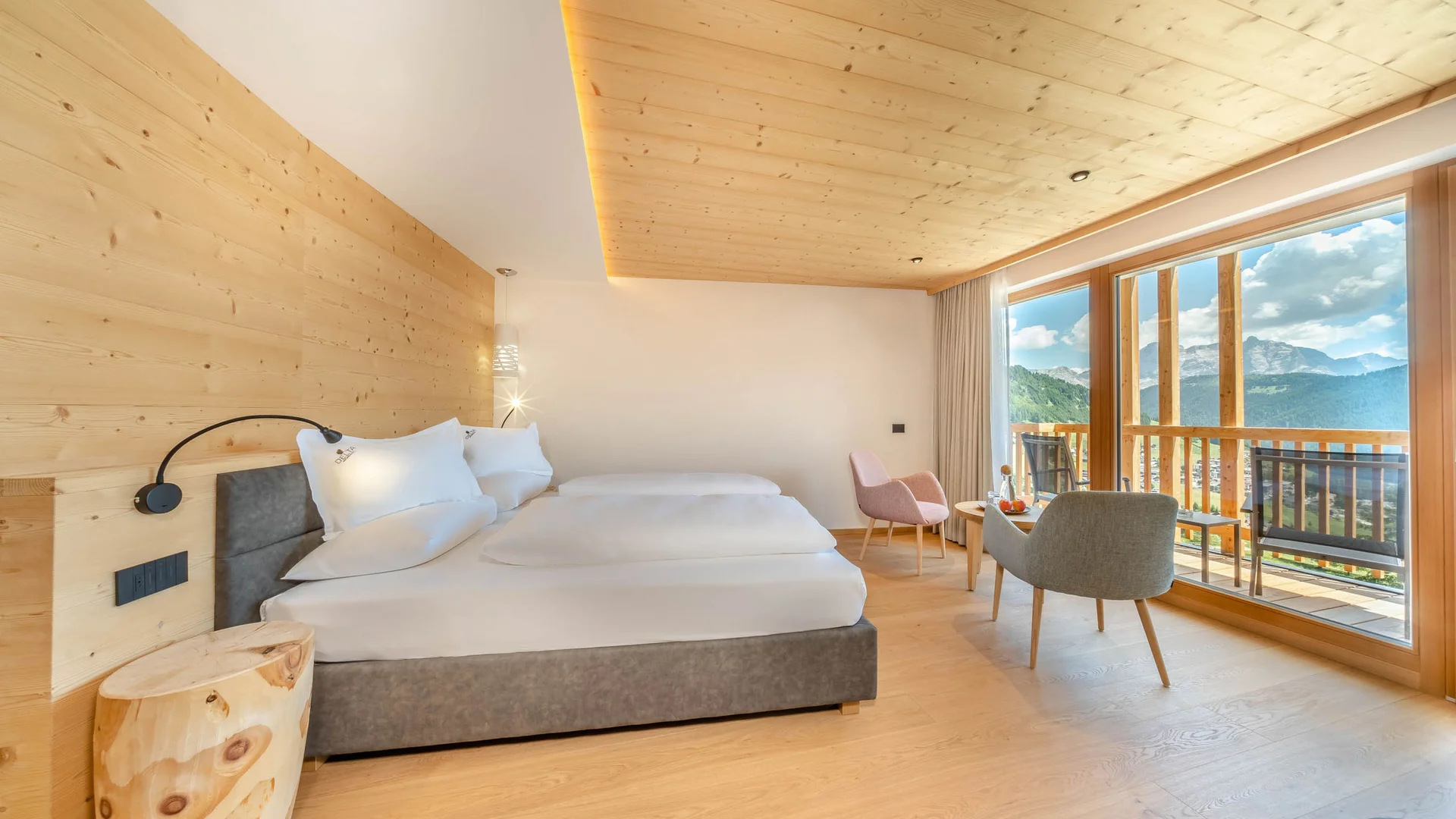 Zuhause auf Zeit im Hotel in Colfosco: Nature Hotel Delta Modernes Hotelzimmer mit Holzwänden, Doppelbett und Bergblick vom Balkon