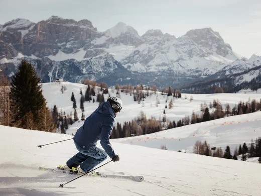 Zuhause auf Zeit im Hotel in Colfosco: Nature Hotel Delta Skifahrer fährt auf verschneiter Piste mit Bergen im Hintergrund
