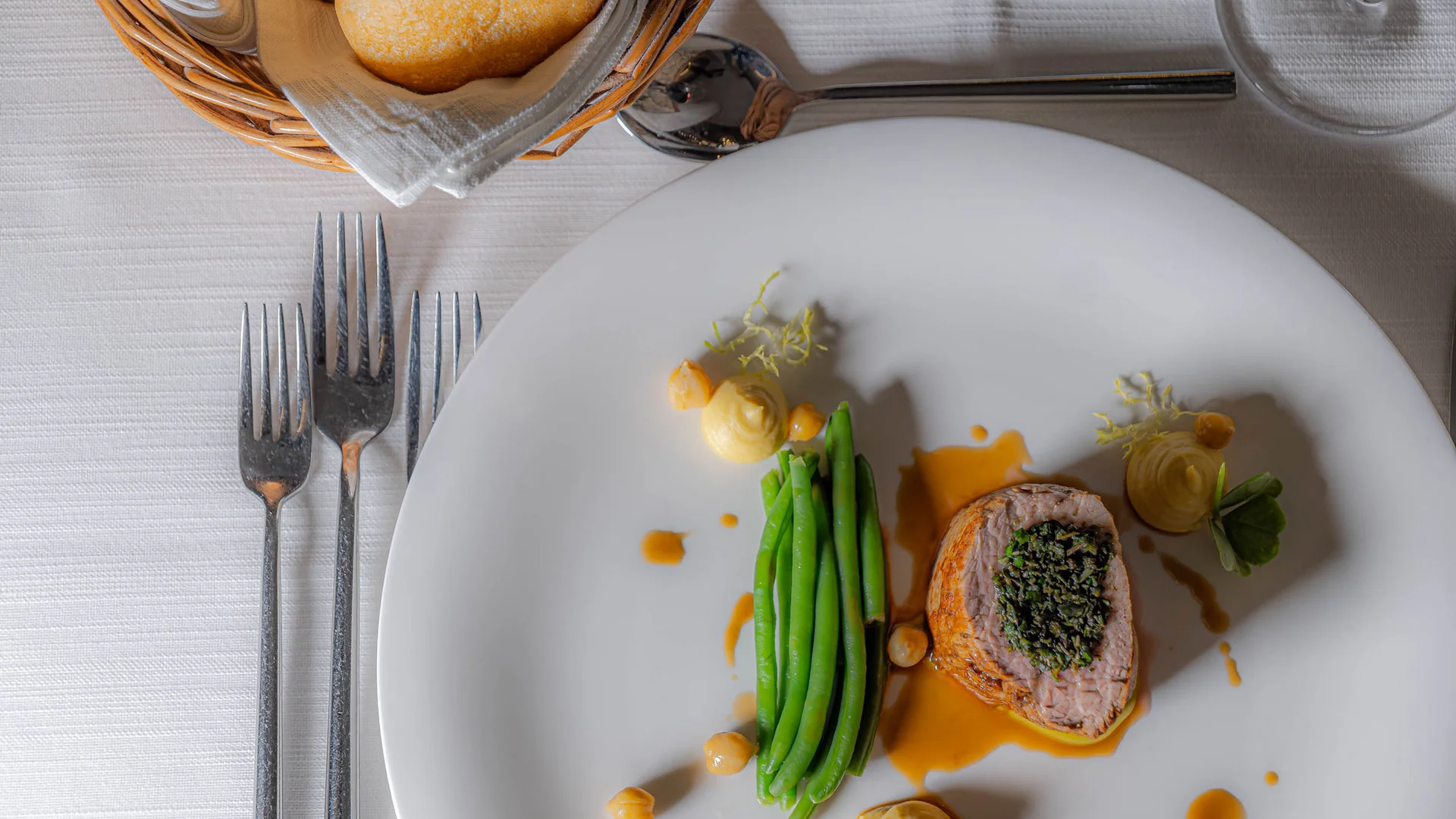 Zuhause auf Zeit im Hotel in Colfosco: Nature Hotel Delta Gourmetgericht mit grünem Gemüse, Fleisch und Soße auf weißem Teller