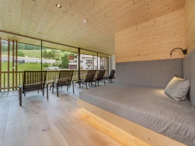 Zuhause auf Zeit im Hotel in Colfosco: Nature Hotel Delta Moderner Ruheraum mit Liegen und Blick auf grüne Wiese und Gebäude